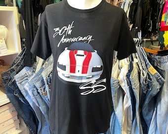 Op de afbeelding: Zwart T-shirt met een witte en rode auto afbeelding en de tekst "30th Anniversary" op de voorkant.