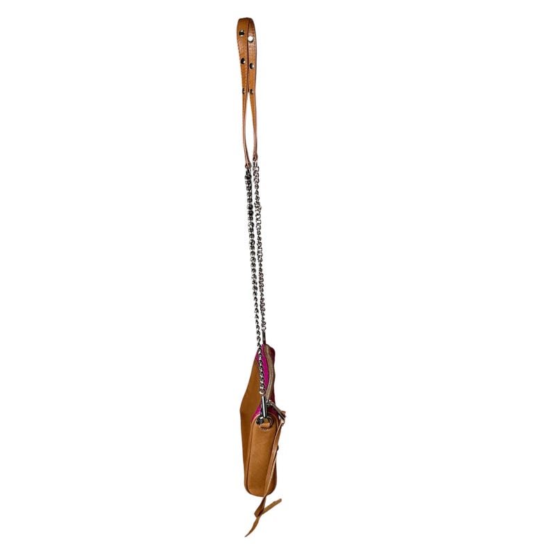 Puede incluir: Un bolso bandolera de cuero marr&oacute;n claro con una correa de cadena plateada y una correa de cuero marr&oacute;n. El bolso tiene un interior rosa y una peque&ntilde;a bolsa adjunta. El bolso cuelga sobre un fondo blanco.