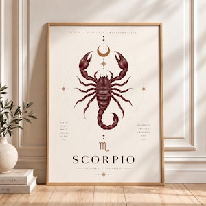May include: A framed wall art print featuring a dark red scorpion illustration centred within a geometric circle. Above the scorpion is a crescent moon and stars. Text includes INTENSE, INTUITIVE, TRANSFORMATIVE, SCORPIO, and OCTOBER 23 - NOVEMBER 21.