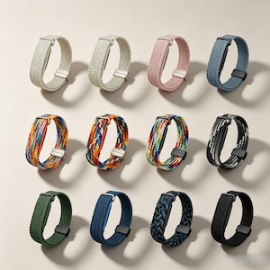 May include: A collection of twelve braided watch bands arranged in three rows. The bands feature various solid colors including white, pink, blue, green, and black, alongside multi-colored woven patterns. Each band includes a metal buckle and clasp.