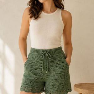 Peut inclure: Shorts en crochet vert sauge dotés d'une taille élastique côtelée avec un cordon de serrage assorti, de poches latérales et d'un ourlet décoratif festonné. Le short est associé à un débardeur côtelé simple, sans manches, de couleur crème.
