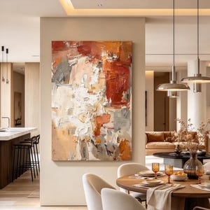 May include: A large rectangular abstract painting featuring thick, textured impasto brushstrokes in shades of burnt orange, cream, white, and muted gray. The artwork is displayed on a neutral-toned wall in a residential interior space.