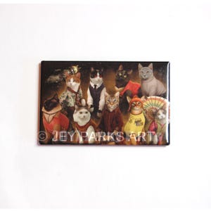 May include: Rectangular magnet featuring a group of cats dressed in various outfits. The cats are of different breeds and colors, wearing clothing such as suits, sweaters, and traditional Japanese attire. The text "© JEY PARKS ART" is visible.