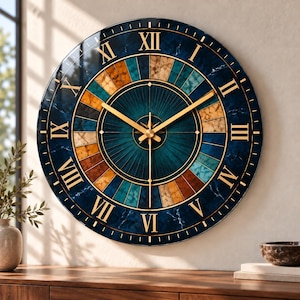 May include: A round wall clock featuring a dark blue marble-patterned face with gold Roman numerals. The center displays a sunburst design in shades of teal, brown, and tan, complemented by thin gold clock hands and a central star-shaped detail.