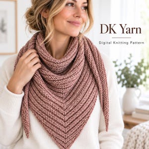 Peut inclure: Un châle triangulaire en tricot rose poudré avec un motif côtelé texturé. Le texte DK Yarn Digital Knitting Pattern est affiché dans le coin supérieur droit. Le châle est drapé autour du cou, mettant en valeur sa pointe en V et sa maille.