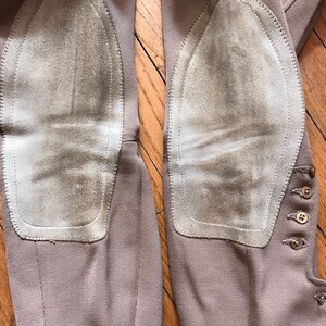 May include: A pair of brown riding breeches with suede knee patches. The breeches have a button closure on the side.