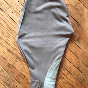 May include: A pair of beige riding breeches with a zipper closure and suede knee patches.