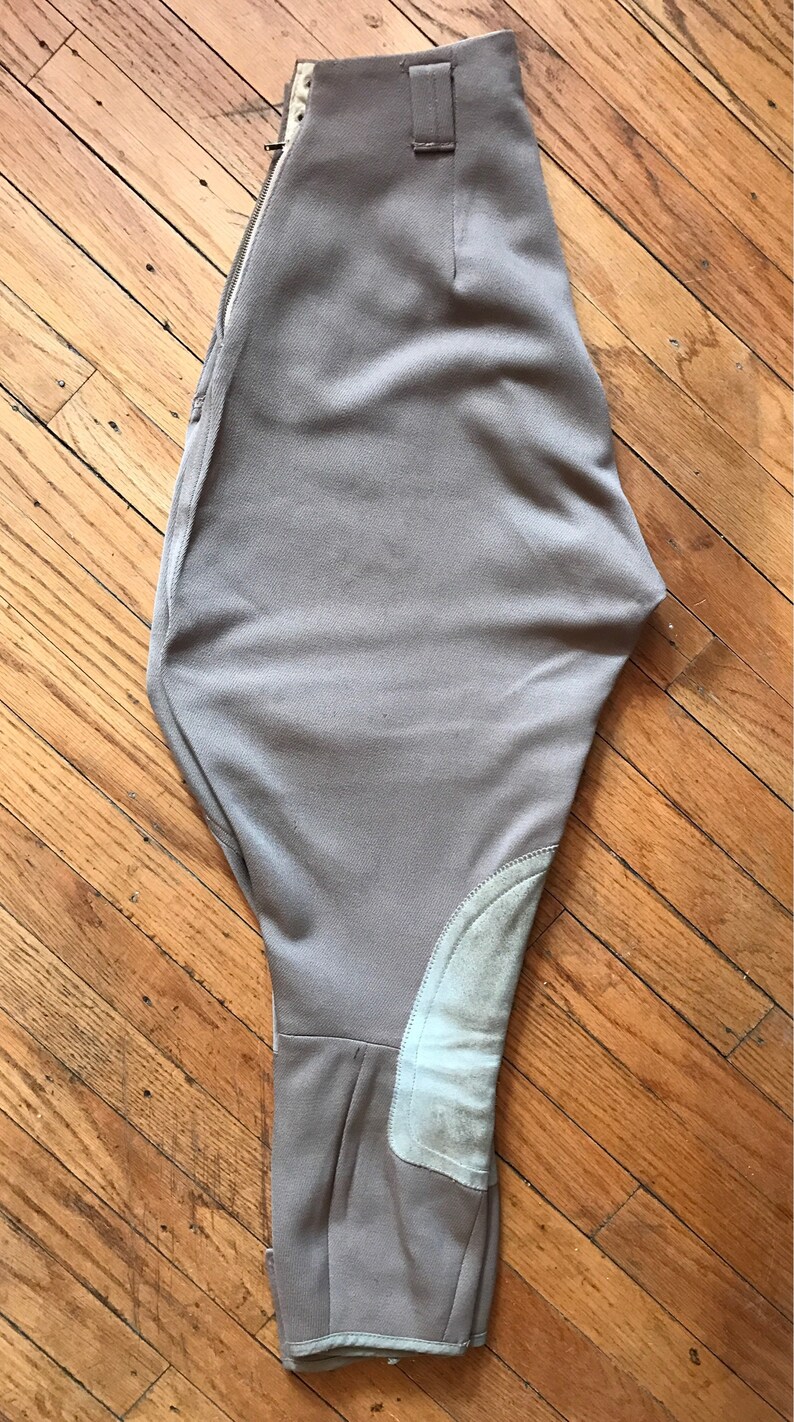 May include: A pair of beige riding breeches with a zipper closure and suede knee patches.