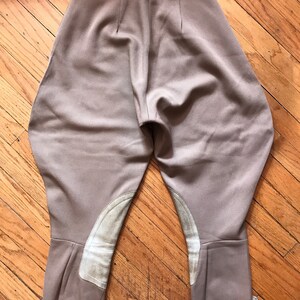 May include: A pair of brown riding breeches with white leather knee patches. The breeches have a high waist and a slim fit.