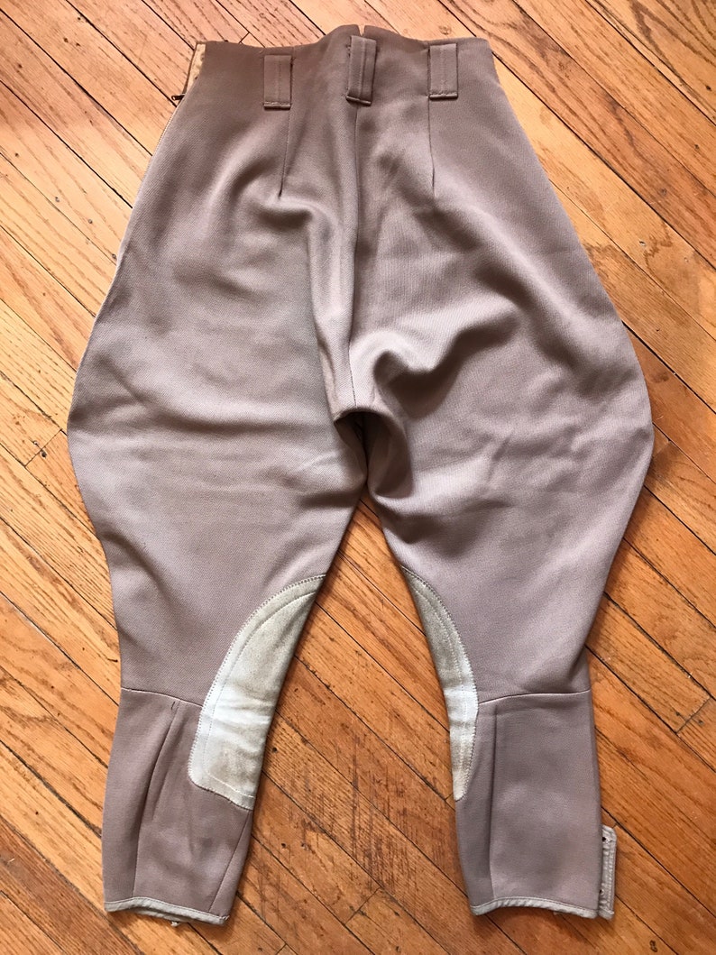 May include: A pair of brown riding breeches with white leather knee patches. The breeches have a high waist and a slim fit.