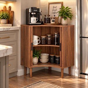 May include: A wooden corner cabinet with two shelves, featuring a De'Longhi coffee machine on top. The cabinet holds white mugs, glass jars, a French press, stacked bowls, and canisters labeled 'Tea' and 'Coffee'. A green plant sits inside.