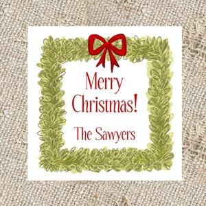 May include: A white Christmas card with a green wreath border and a red bow. The card says "Merry Christmas! The Sawyers".
