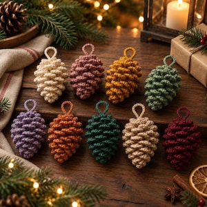May include: A collection of nine crocheted pinecone ornaments in various colors including cream, dusty rose, mustard yellow, sage green, lavender, burnt orange, forest green, beige, and deep burgundy, each featuring a small loop for hanging.