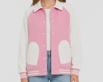 Peut inclure: Une veste de style universitaire avec un corps rose et des manches blanches. La veste présente un col blanc, une fermeture à boutons sur le devant et deux grandes poches blanches en forme de cœur. Les poignets et l'ourlet ont des rayures.