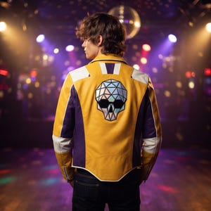 Puede incluir: Una chaqueta de cuero amarilla, morada y blanca con un gráfico grande de un cráneo geométrico e iridiscente en la espalda. La chaqueta tiene un cuello estructurado, mangas largas con puños de cremallera y un diseño de paneles con detalles blancos.
