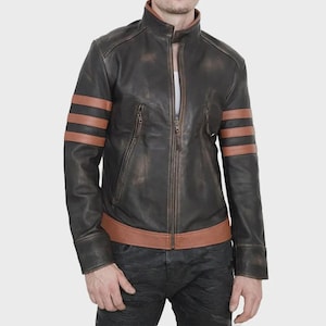 Può includere: Una giacca in pelle marrone scuro con colletto alla coreana, chiusura frontale con zip e due tasche verticali con zip sul petto. Le maniche sono decorate con tre strisce orizzontali color cuoio e l'orlo è rifinito con una fascia in pelle.