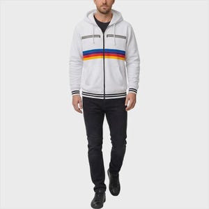 May include: A white zip-up hoodie featuring a horizontal rainbow stripe across the chest, two zippered chest pockets, and black and white striped ribbed cuffs and hem. The hoodie is paired with dark charcoal denim jeans and black sneakers.