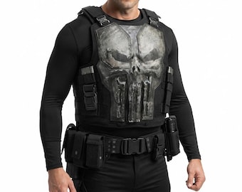 May include: A black tactical vest featuring a large, weathered, grey skull graphic on the chest plate. The vest includes integrated shoulder straps, multiple utility pouches, and heavy-duty buckles. It is worn over a black long-sleeve shirt.