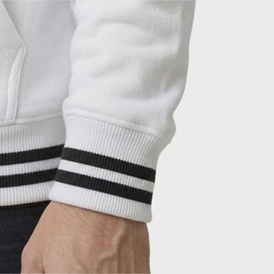 May include: A white long-sleeved sweatshirt featuring a ribbed cuff at the wrist. The cuff is white with two distinct horizontal black stripes running around the circumference, providing a contrasting detail against the solid white fabric of the sleeve.