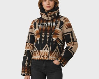 Peut inclure: Une veste courte ornée d'un motif géométrique dans des tons de noir, de beige et de brun. Le vêtement présente un col montant avec une bride à boucle, des manches longues et une fermeture éclair diagonale, portée avec un jean gris foncé.