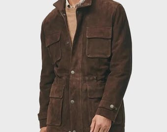 Peut inclure: Une veste en daim marron foncé dotée d'un col montant, d'une fermeture à boutons sur le devant et de quatre grandes poches à rabat. La veste présente des manches longues avec des poignets boutonnés et une coupe structurée sur une chemise beige.