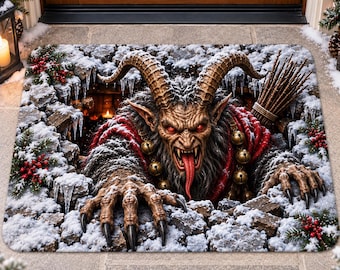 May include: A rectangular doormat featuring a 3D-style illustration of a horned, furry creature with red eyes, a long tongue, and gold bells, emerging from a snowy, rocky pit decorated with pine branches and red berries.