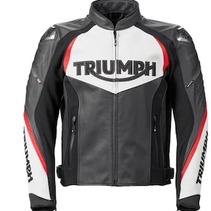 May include: A black, white, and red motorcycle jacket featuring the word TRIUMPH in black lettering across the chest and on the sleeves. The jacket has a high collar, a full-length front zipper, and protective shoulder panels with a textured finish.