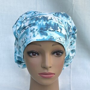 May include: A blue and white patterned surgical scrub hat with a tie at the back. The hat is on a mannequin head.