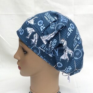 May include: Blue and white patterned scrub hat with a tie. The hat features a graphic design with the text "Jedi Warrior" and "Bravery, Hope, Wisdom".