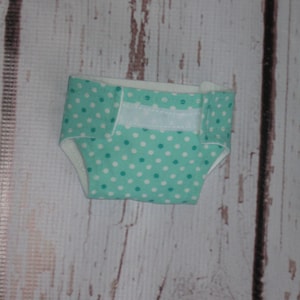 May include: A turquoise and white polka dot diaper with white velcro closures.