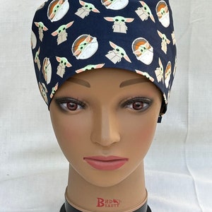 May include: A dark blue scrub hat with a repeating pattern of small green alien characters. The hat is made of a soft, comfortable fabric and is perfect for healthcare professionals.