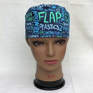May include: A blue and green surgical scrub hat with a variety of medical terms printed on it, including "FLAP", "PLASTICS", and "CONTRACTURES".