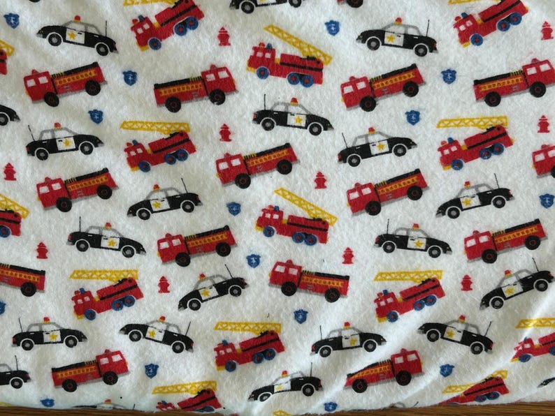 K&ouml;nnte beinhalten: Wei&szlig;er Stoff mit einem sich wiederholenden Muster aus roten Feuerwehrautos, schwarz-wei&szlig;en Polizeiautos, gelben Leitern, blauen Schilden und roten Hydranten. Geeignet f&uuml;r Kinderartikel.