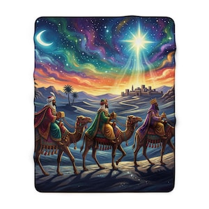May include: A rectangular fleece blanket featuring a colourful illustration of three figures riding camels across a desert landscape towards a distant city under a vibrant night sky with a crescent moon and a bright, glowing star shining above.