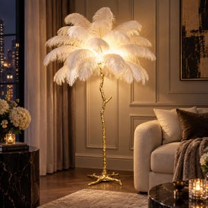 May include: A floor lamp featuring a gold-colored base shaped like a textured tree branch with a wide, rounded shade composed of numerous white ostrich feathers that emit a soft, warm glow from the internal light source.