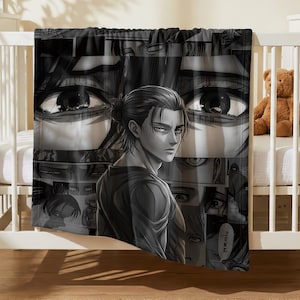 May include: A black and white throw blanket featuring a collage of manga panels from Attack on Titan. The design prominently displays a central character with dark hair tied back, surrounded by various close-up illustrations of eyes and scenes.