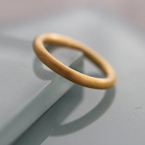 May include: A simple gold band ring with a brushed finish.