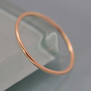 May include: A simple, thin, gold band ring. The ring is smooth and polished.