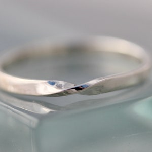 May include: A silver twisted band ring. The ring is smooth and has a polished finish.