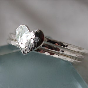 May include: A set of three silver rings with a hammered finish. The top ring features a heart-shaped design.