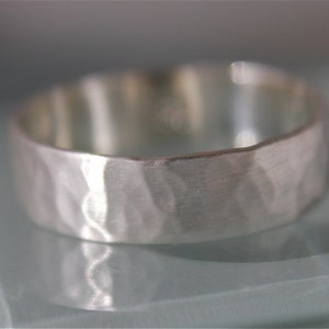 May include: A silver hammered band ring with a textured surface.