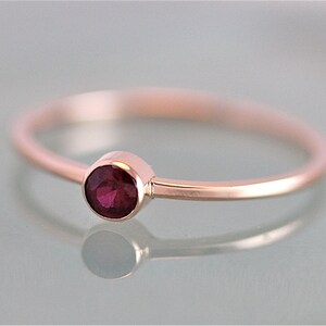 Op de afbeelding: Een delicate ring van ros&eacute;goud met een enkele, ronde, dieprode edelsteen.