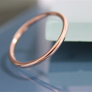 May include: A simple, thin rose gold band ring.
