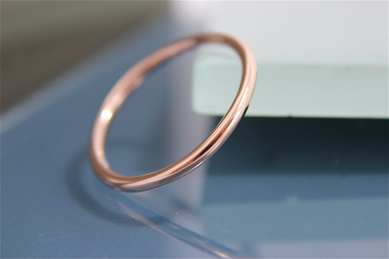 May include: A simple, thin rose gold band ring.