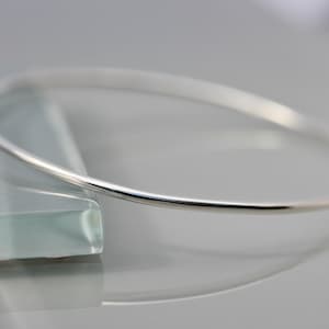 May include: A simple silver bangle bracelet, a classic and elegant piece of jewelry.