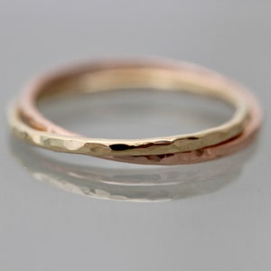 May include: A triple band ring with a hammered finish. The bands are made of yellow gold, rose gold, and white gold.