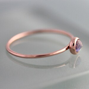May include: A delicate rose gold ring with a small, round, iridescent gemstone.