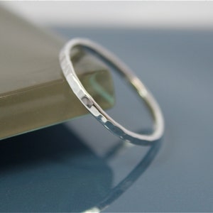 May include: A thin silver ring with a hammered texture. The ring is simple and delicate.