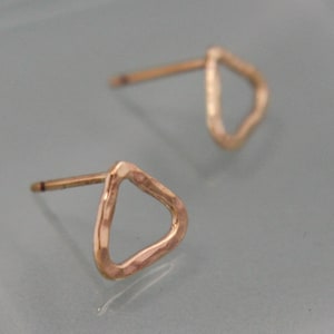 May include: A pair of gold-toned triangle shaped earrings with a hammered texture.