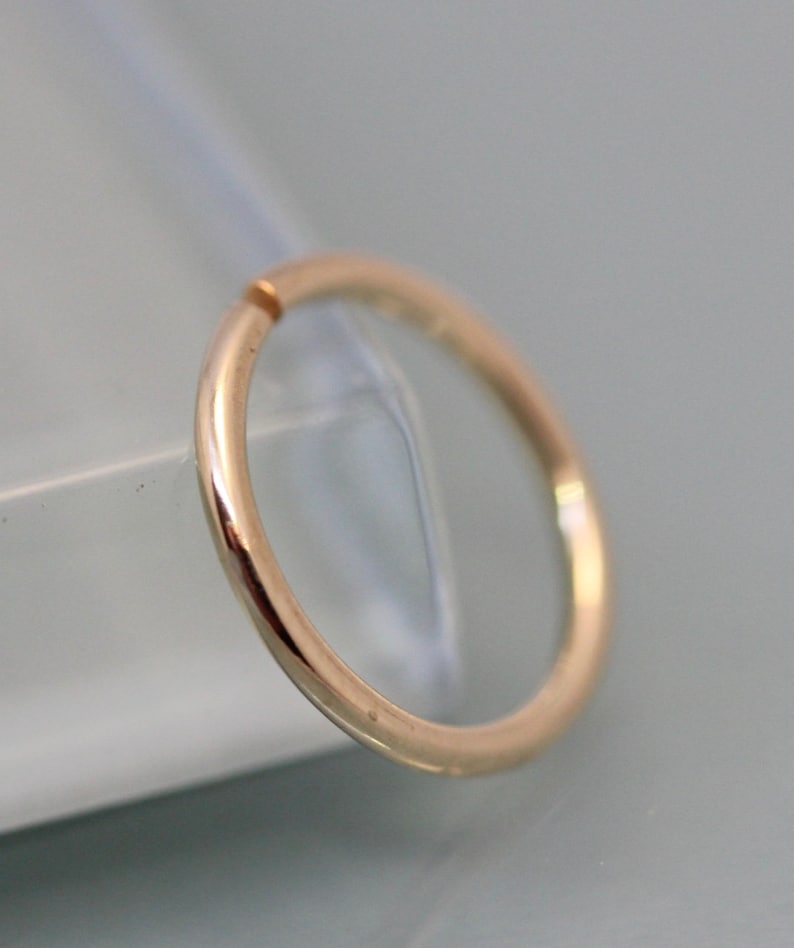 May include: A gold-colored seamless hoop ring, a type of body jewelry.